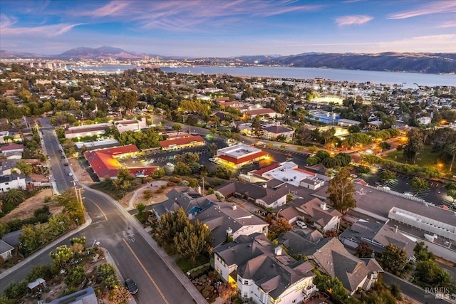 aerial view at dusk featuring a water and mountain view