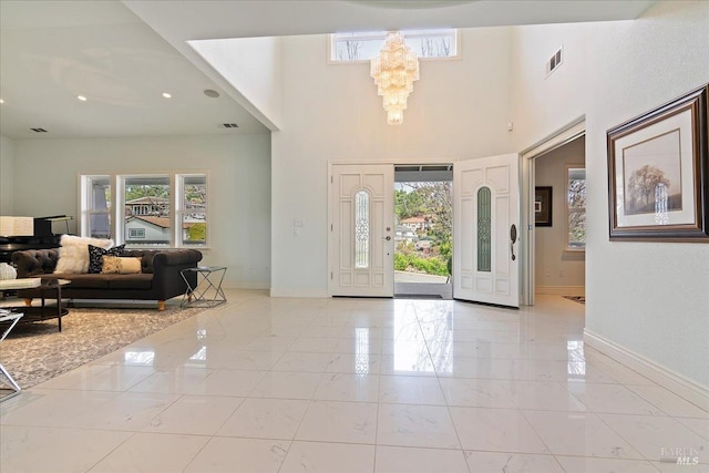 foyer entrance with an inviting chandelier, a high ceiling, and a wealth of natural light