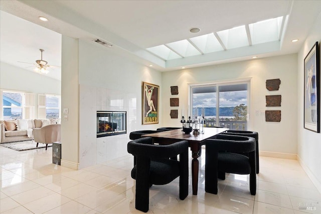 tiled dining area featuring ceiling fan, plenty of natural light, lofted ceiling, and a fireplace