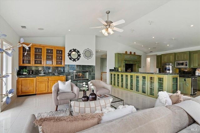 tiled living room featuring vaulted ceiling, a premium fireplace, and ceiling fan