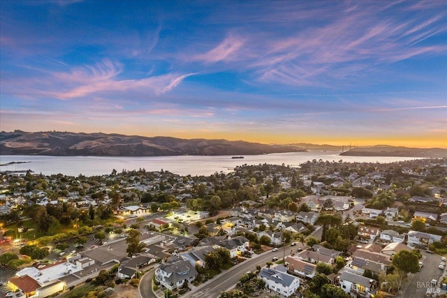 aerial view at dusk featuring a water and mountain view