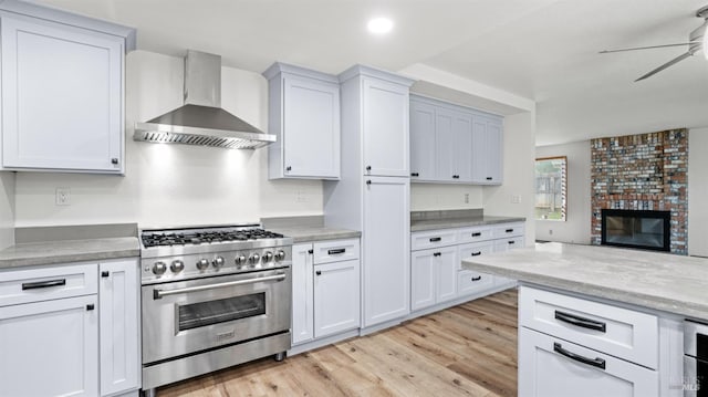 kitchen featuring white cabinetry, ceiling fan, stainless steel range, and wall chimney exhaust hood