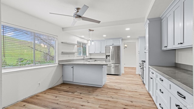 kitchen featuring sink, hanging light fixtures, stainless steel fridge, kitchen peninsula, and light hardwood / wood-style floors