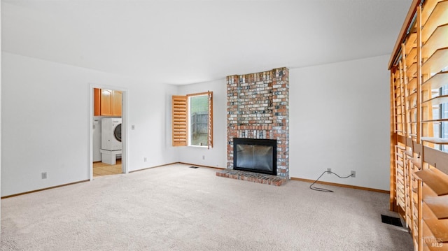 unfurnished living room featuring light carpet, washer / clothes dryer, and a fireplace