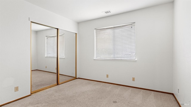 unfurnished bedroom featuring light colored carpet and a closet