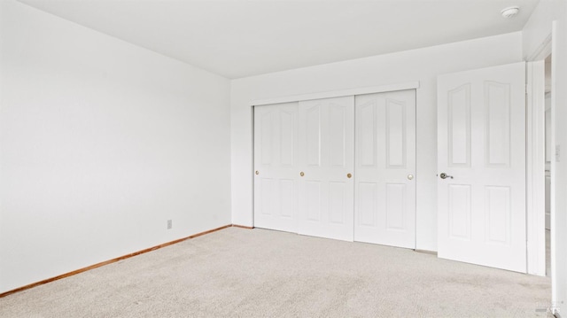 unfurnished bedroom featuring light carpet and a closet