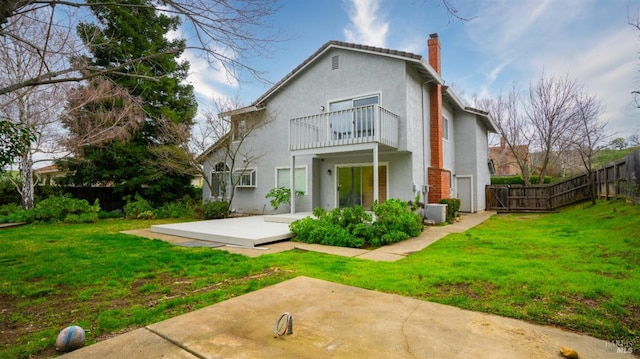 rear view of house with a patio, a balcony, and a yard