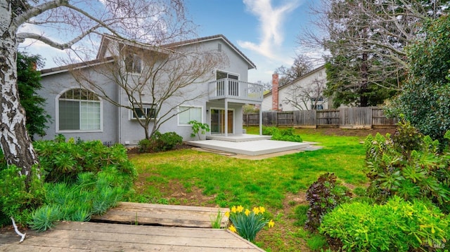 rear view of property with a yard and a balcony