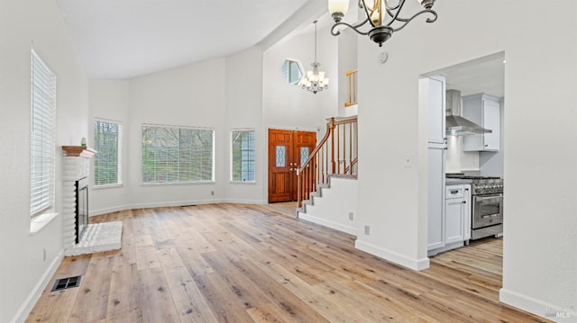 unfurnished living room with an inviting chandelier, a fireplace, and light wood-type flooring