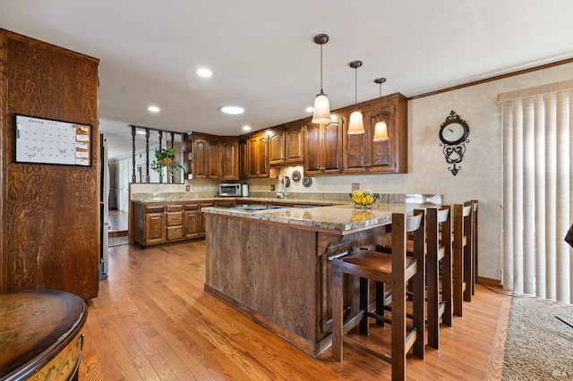 kitchen featuring pendant lighting, crown molding, light stone countertops, light hardwood / wood-style floors, and kitchen peninsula