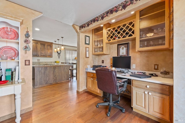 office space with built in desk and light hardwood / wood-style floors