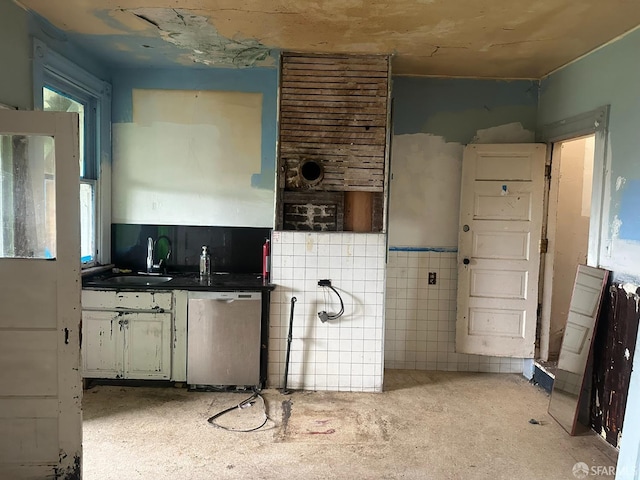 kitchen featuring dishwasher, sink, and tile walls