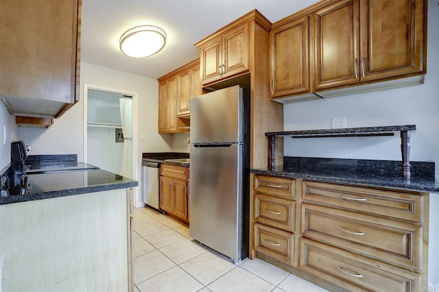 kitchen featuring dark stone countertops, appliances with stainless steel finishes, and light tile patterned floors