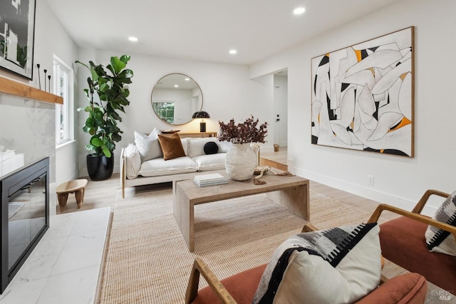 living room featuring a high end fireplace and light hardwood / wood-style flooring