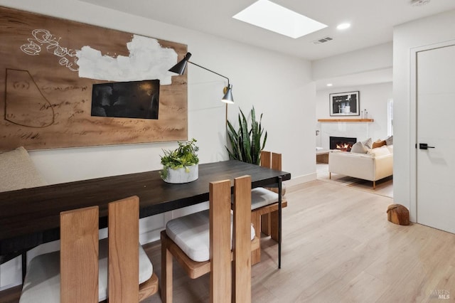 dining area with light wood-type flooring and a skylight