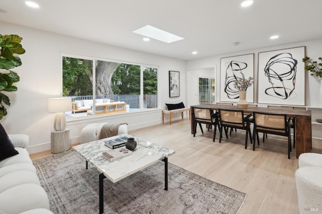 living room with a skylight and light hardwood / wood-style floors