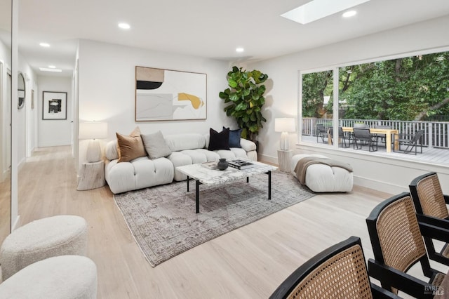 living room featuring light hardwood / wood-style flooring and a skylight