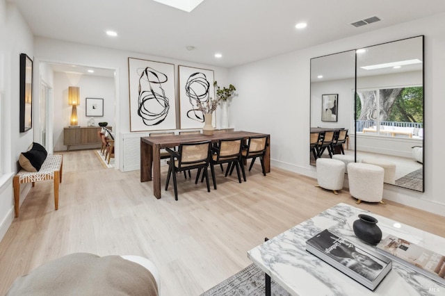 living room with a skylight and light hardwood / wood-style floors