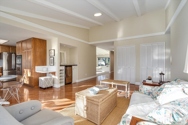 living room with beverage cooler, beam ceiling, and light hardwood / wood-style floors