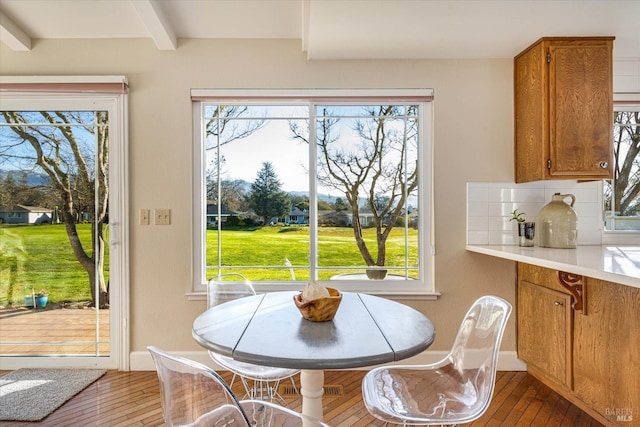 dining space featuring beam ceiling, wood-type flooring, and a healthy amount of sunlight