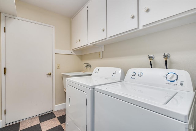 clothes washing area with cabinets and washer and dryer