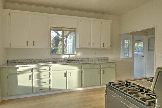 kitchen featuring white cabinetry, sink, light hardwood / wood-style flooring, and gas range oven