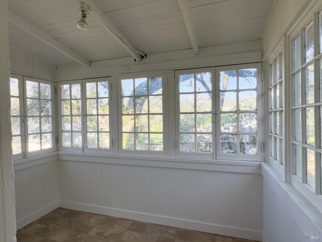 unfurnished sunroom featuring lofted ceiling with beams and wooden ceiling