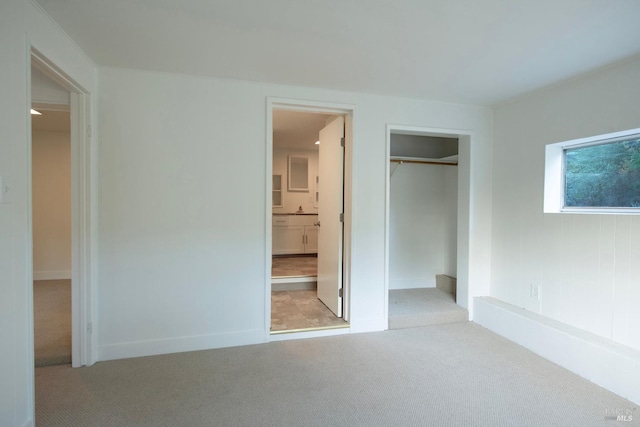 unfurnished bedroom featuring light colored carpet, ensuite bathroom, and a closet