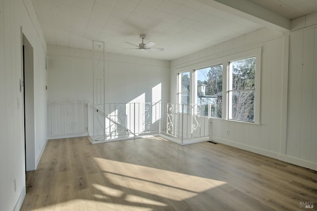 spare room featuring ceiling fan, beam ceiling, and light wood-type flooring