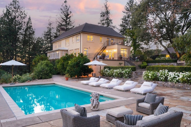 outdoor pool with outdoor lounge area, stairs, and a patio area