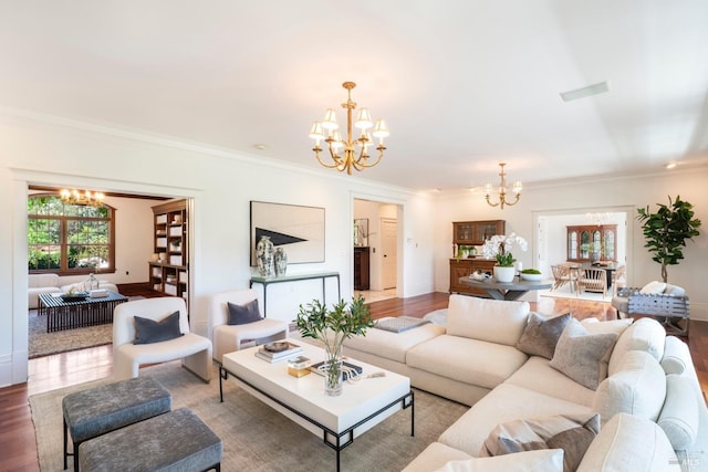 living room with an inviting chandelier, wood finished floors, visible vents, and ornamental molding