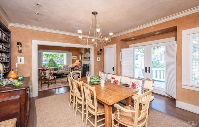 dining space featuring hardwood / wood-style flooring, ornamental molding, an inviting chandelier, and a textured ceiling