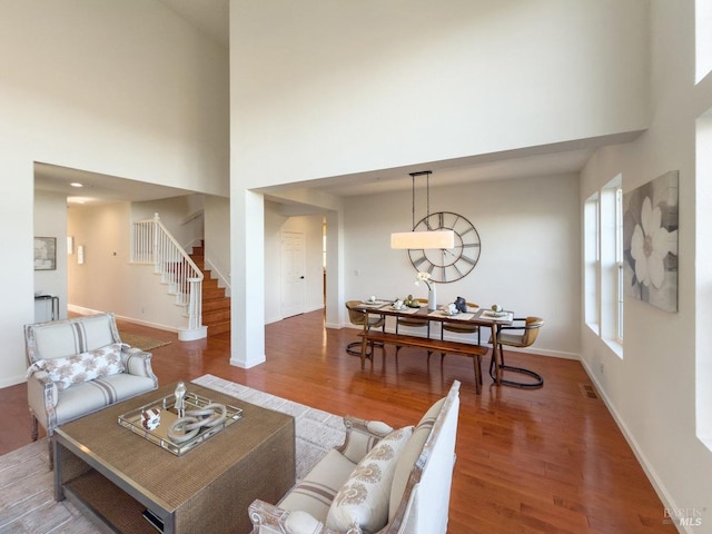 living room with a towering ceiling and wood-type flooring