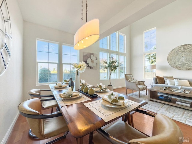 dining space with hardwood / wood-style floors and a towering ceiling