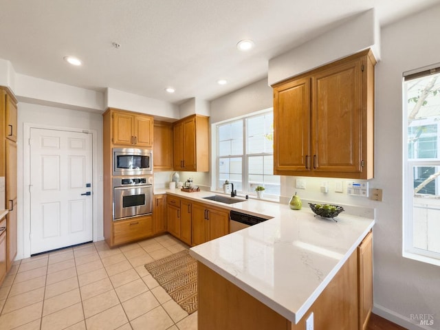 kitchen with sink, light stone counters, light tile patterned floors, appliances with stainless steel finishes, and kitchen peninsula