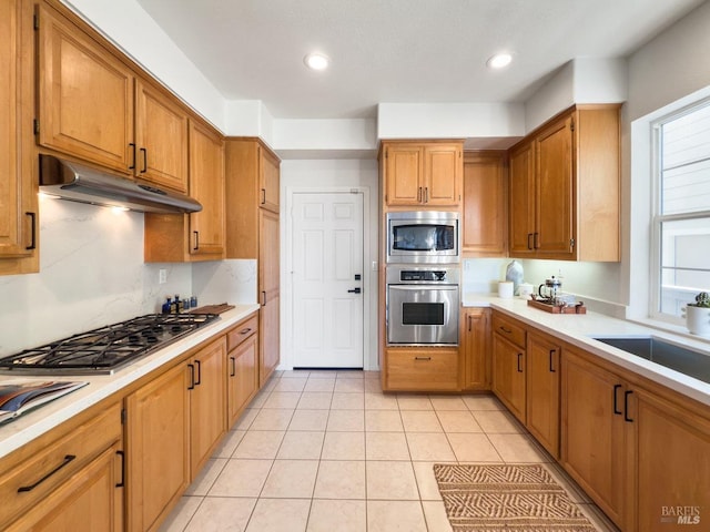 kitchen featuring tasteful backsplash, sink, light tile patterned floors, and stainless steel appliances