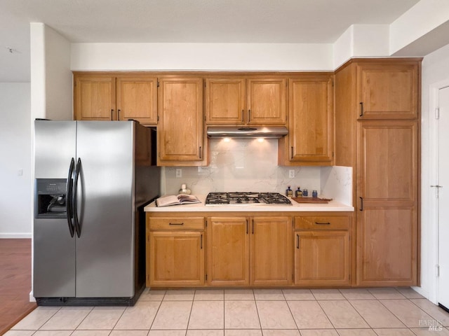 kitchen with appliances with stainless steel finishes, light tile patterned floors, and backsplash