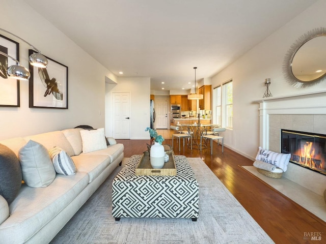 living room with dark wood-type flooring and a tile fireplace