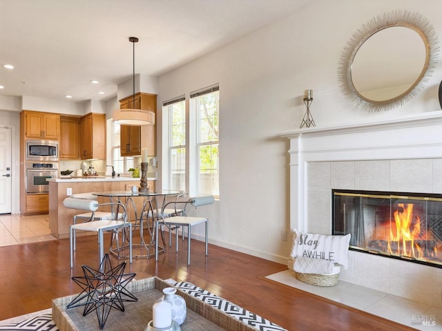 interior space featuring a kitchen bar, hanging light fixtures, kitchen peninsula, stainless steel appliances, and light wood-type flooring