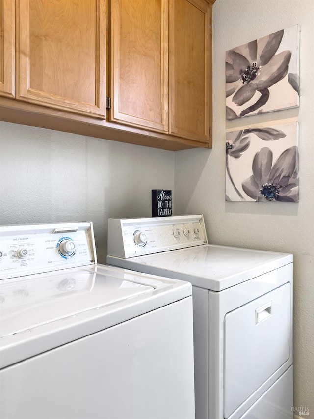 clothes washing area featuring cabinets and washing machine and clothes dryer