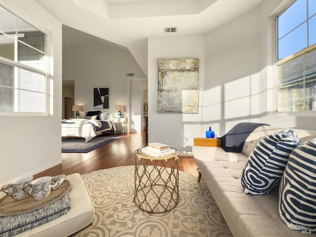 living room featuring a towering ceiling, wood-type flooring, and a wealth of natural light