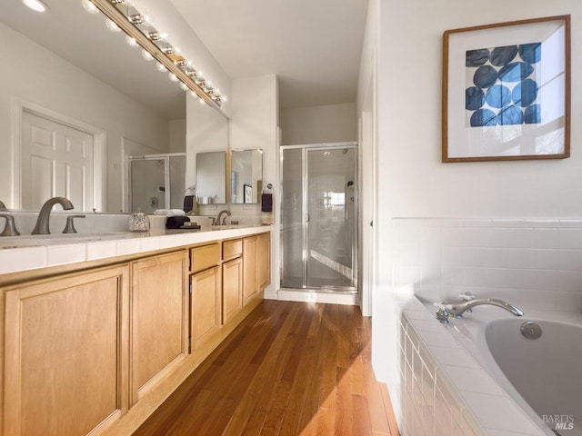 bathroom with vanity, hardwood / wood-style floors, and plus walk in shower