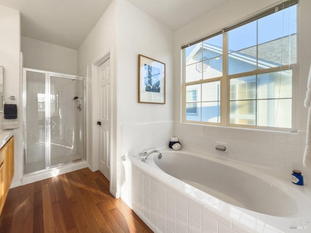 bathroom with plus walk in shower, hardwood / wood-style floors, and vanity