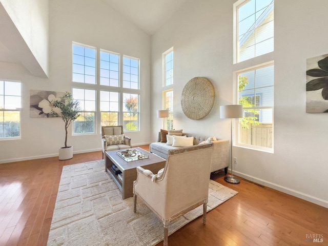 living room featuring a healthy amount of sunlight, high vaulted ceiling, and light wood-type flooring