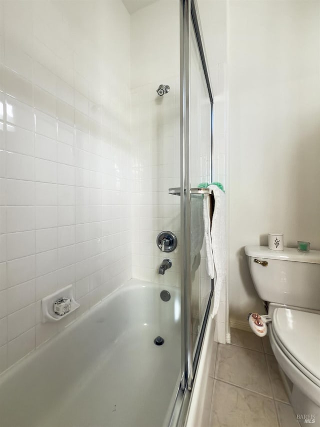 bathroom featuring bath / shower combo with glass door, tile patterned floors, and toilet