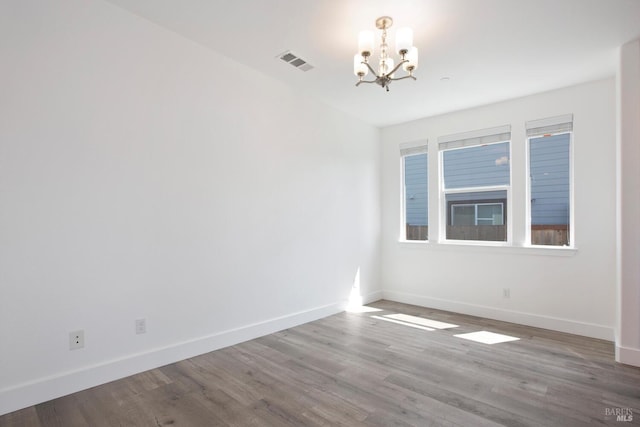 spare room with hardwood / wood-style flooring and a chandelier