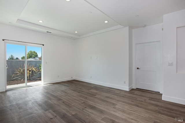 empty room featuring dark wood-type flooring and a raised ceiling