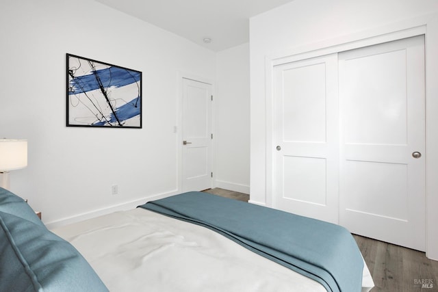 bedroom with dark hardwood / wood-style flooring and a closet