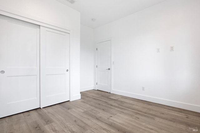 unfurnished bedroom featuring light hardwood / wood-style floors and a closet