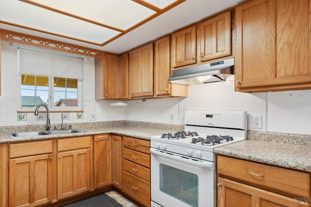 kitchen featuring under cabinet range hood, a sink, backsplash, light countertops, and white range with gas stovetop